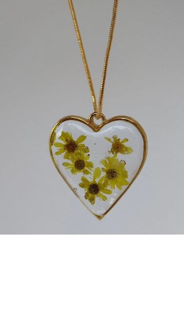 Heart shaped pendant with small yellow flowers cast in resin.