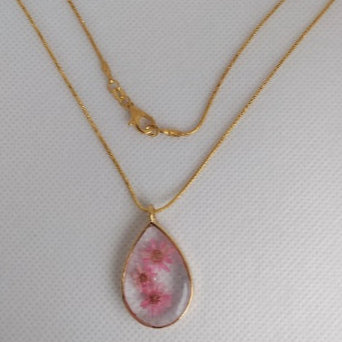 Tear drop pendant with small flowers cast in resin.