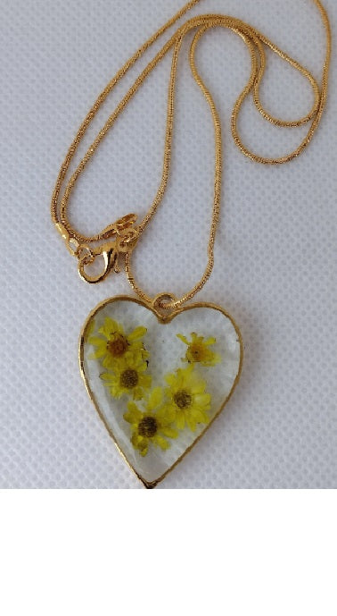 Heart shaped pendant with small yellow flowers cast in resin.